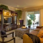 living room with zebra patter ottoman, giraffe pattern floor lamp, wooden entertainment cabinet, brown sofa
