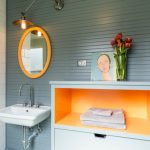bathroom color trends wall mounted sink round mirror hanging lamp orange shelf white tile grey backsplash contemporary design