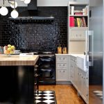 black tiled backplash black appliances black hood black island white cabinet wooden countertop ceiling lamps wooden floor