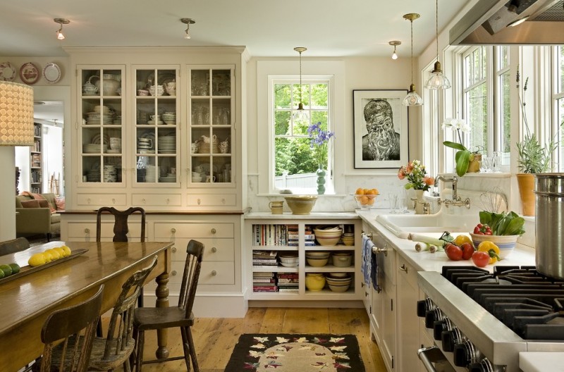 Farmhouse eat in kitchen with a drop in sink, open cabinets, glass doors cabinets, white cabinets, white backsplash, marble countertops and stone slab backsplash