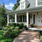 front porch and lawn with flower beds evergreen shrubs brick pathways in patterns medium colored wooden floors patio white doors and fences
