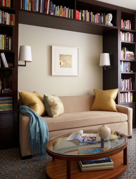 home library with brown wooden bookcases with nook filled with sofa, round coffee table