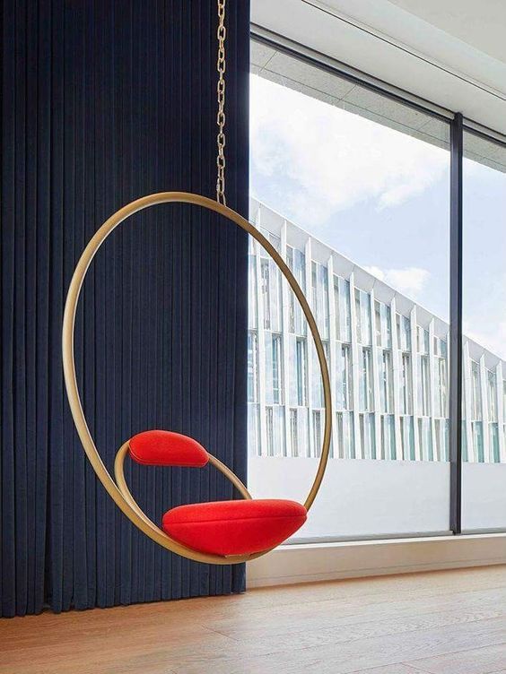 modern swing with goden ring and a chair with red small cushion on the ring