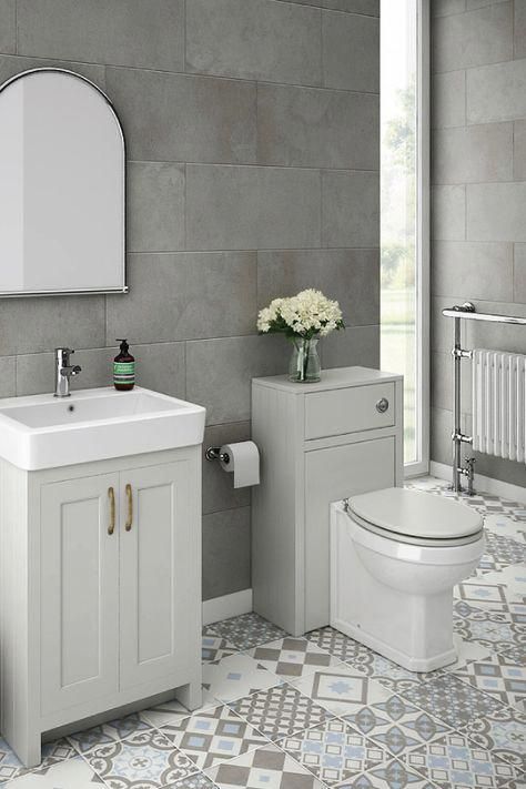 bathroom with white toilet, white cabinet, white sink, mirror, grey and white pattern tiles with different color and patterns