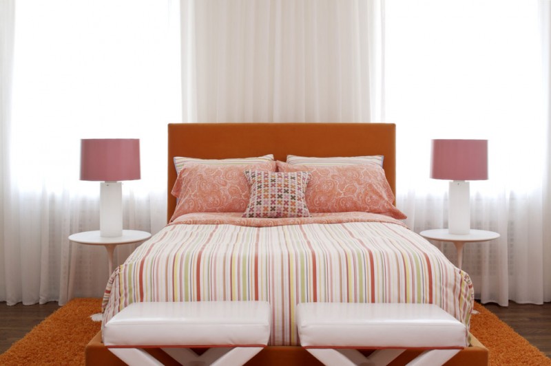 bedside table height orange headboard orange shag rug striped bedding pink table lamps white pedestal side tables white benches glass windows white curtain