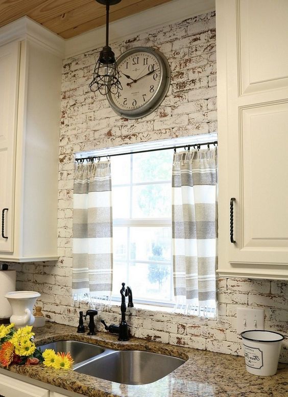 kitchen with white open brick wall, white cabinet, brown kitchen top, windows, silver sink with black faucet