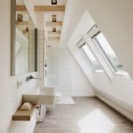Long Bathroom With Slope Ceiling, Wooden Floor Tiles, White Walls, White Wall Tiles, Glass Windows On Slope Ceiling, Mirror, White Toilet, White Sink,