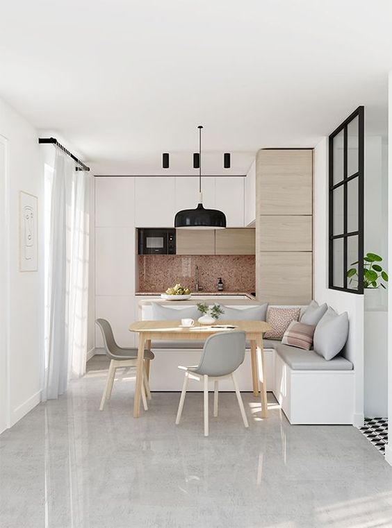 open room with white marble floor, white wooden cabinet with marble backsplash, white bench with thin grey cushion, wooden table