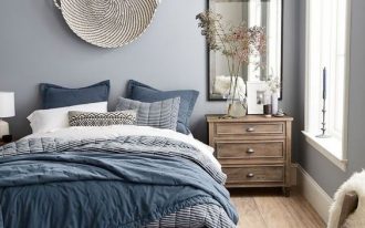 bedroom, wooden floor, blue rug, blue bedding, wooden bed platform, light blue wall, white pattern textured ceiling, wooden bedsde cabinet, mirror, wooden chair