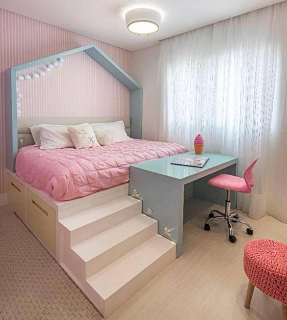 bedroom, wooden floor, rug, high bed platform with pink bedding, storage under, blue study table, pink chair, pink crochette seating stool, pink wall, white curtain