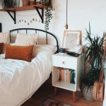 Bedroom, Wooden Floor, Rug, White Wall, White Bedding, Black Metal Platform, Floating Shelves, White Bedside Shelves, Plants