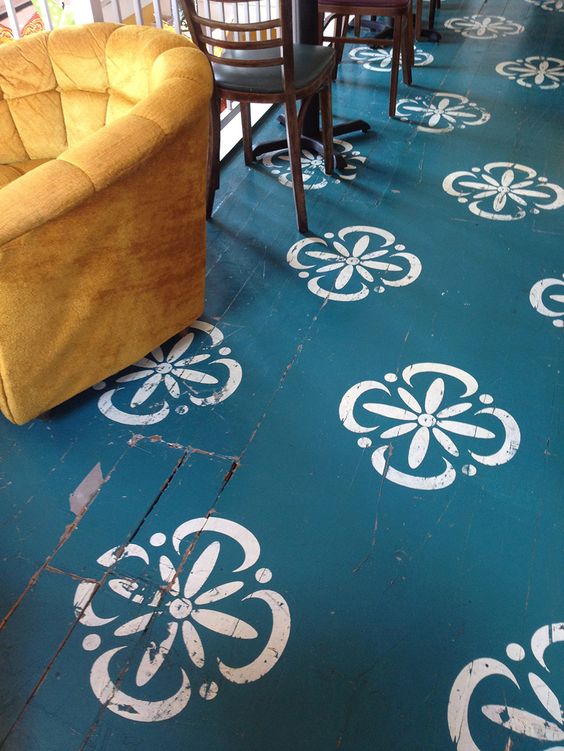 blue painted deck with white flowery patterns, mustard chair, wooden chairs