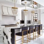Chandelier Pendants On Gold And Crytal Look, White Black Marble Island, Black Cushion Stool With Golden Legs, White Wall, White Cabinet, White Floor