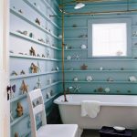 Coastal Bathroom, Blue Wooden Wall With Shelves The Entire Wall, Shells And Starfishes On The Entire Wall, White Tub, White Chairs, Black Stool