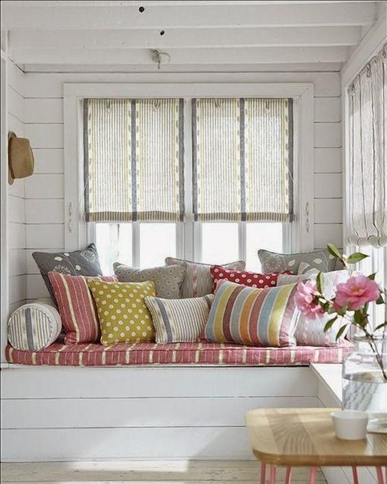 window nook with wooden bench, pink cushion, pillows, white wooden wall, white wooden ceiling, windows with shade