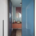 Bathroom With Soft Blue Wall, Purple Lines On The Wall On The Back Of The Mirror, Wooden Vanity, Dark Brown Top, Golden Sink, Stone Tiles, Blue Glass Door