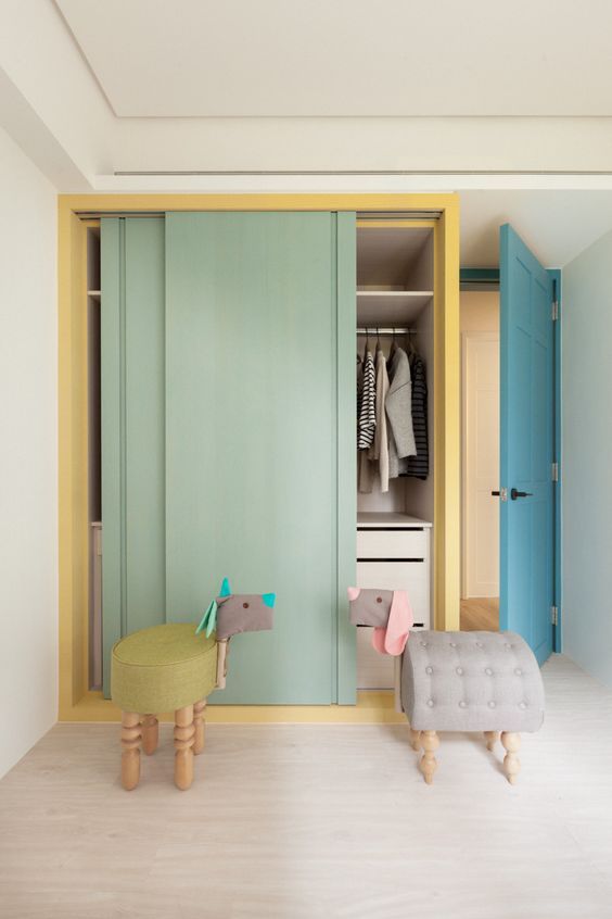 built in cupboard with green sliding door, yellow frame, drawers and shelves inside