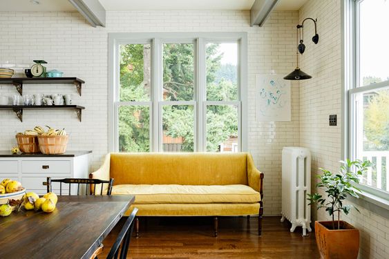 classic minimalist yellow sofa, wooden floor, white subway wall, wooden dining set, sconces, open floating shelves