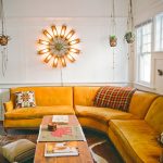 Curvy Corner Yellow Sofa, Rug, White Wall, Hanging Plants, Rectangular Wooden Coffee Table