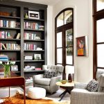 Dark Tall Bookcase, Grey Chairs, White Wall, Tall Windows Brown Wooden Framed, Beige Floor, Rug, Round Coffee Table
