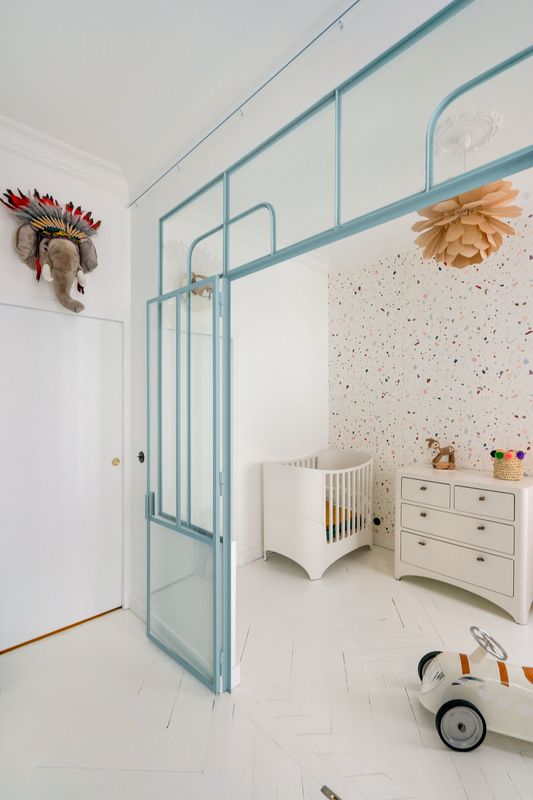 glass partition to white nursery, blue frame, white wooden floor, white cabinet, white crib, orange pendant