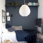Small Bedroom For Teen Boy, Navy Statement Wall With Floating Shelves, White Pendant, Wooden Floor, Rug, Black Basket, TV
