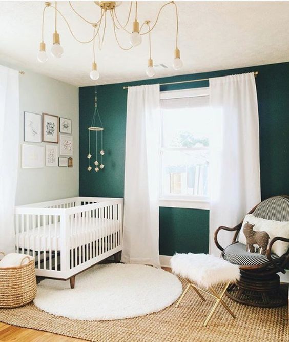 nursery, green wall, white wall, white curtain, rattan rug, white wooden crib, rattan basket, rattan chairs with stool with fur cushion