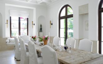rustic dining table white tray ceiling wall sconces white skirt chairs arched glass doors glass windows white shade window seat