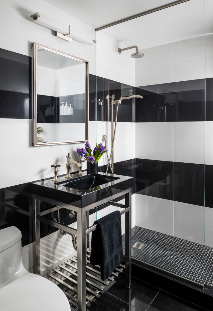small bathroom black and white wall tiles wall mirror shower fixtures glass barrier black mosaic floor tiles chrome pedestal vanity black sink toilet faucet wall sconce