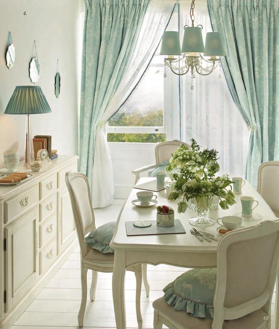 white dining table, white chairs, white wooden floor, white wall, white classy cabinet, blue chandelier, blue curtain