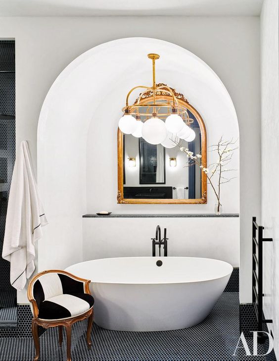 bathroom, black floor tiles, white tub under the white arch, white balls chandelier, black white chair