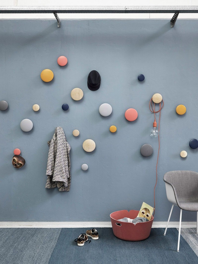 blue wall, round colorful hooks on the wall, lue rug, grey chair, pink bucket, lamp