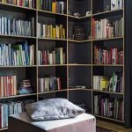 Dark Cornered Book Shelves, Square Ottoman, Wooden Floor, Red Rug