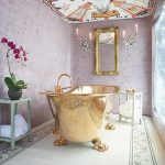 Golden Tub With Golden Claw Foot, White Floor With Pattern Lines, Pink Wall Patterned Statement Ceiling, Golden Framed Mirror, Sconces