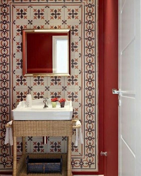 powder room, red wall, patterned wall tiles, rattan vanity, white sink, mirror