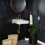Black Vertical Long Tiles, White Cloating Sink, Black White Patterned Floor Tiles, Black Patterned Wall, Red Rug, Round Wooden Mirror