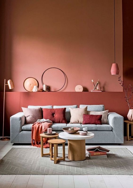 living room, wooden floor, terracotta wall, pink pendant, grey sofa, round coffee tables, grey rug
