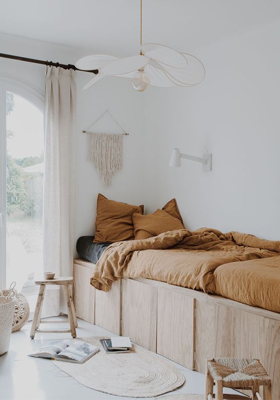 bedroom, white floor, plywood bed platform, white wall, white pendant, rug, rattan stools,