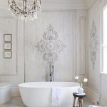 Batroom, White Wooden Floor, White Wall With Details, White Tub, White Toilet, Crystal Chandelier