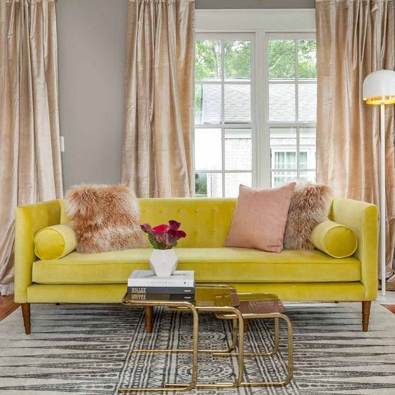 living room, yellow sofa, wooden floor, patterned rug, golden nesting coffee table, brown curtain