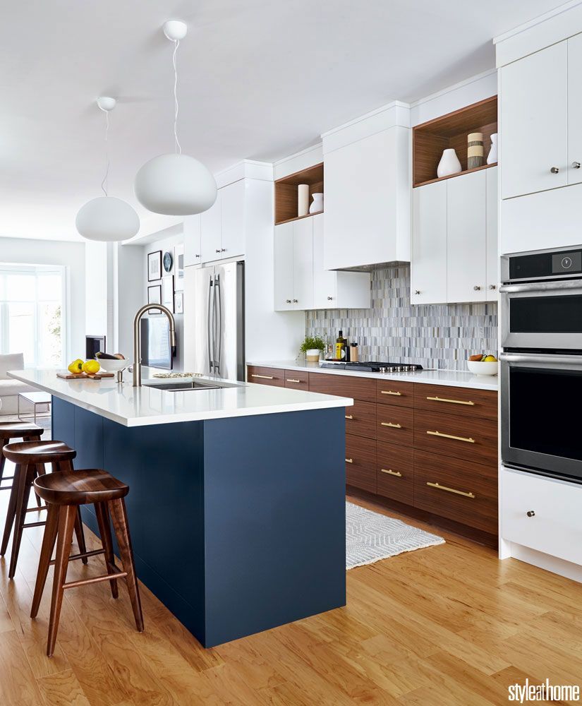 kitchen, wooden floor, white upper cabinet, wooden bottom cabinet, grey backsplash, dark blue island white counter top, white top pendant, wooden stools