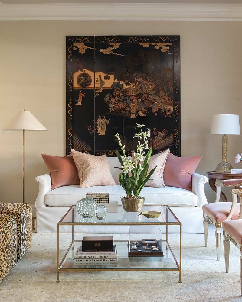 living room, white floor, cream wall, white floor, white table lamp, white sofa, animal print ottoman, pink chairs