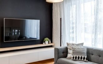living room, wooden floor, black wall, white floating cabinet, grey corner sofa, white coffee table, floor lamp