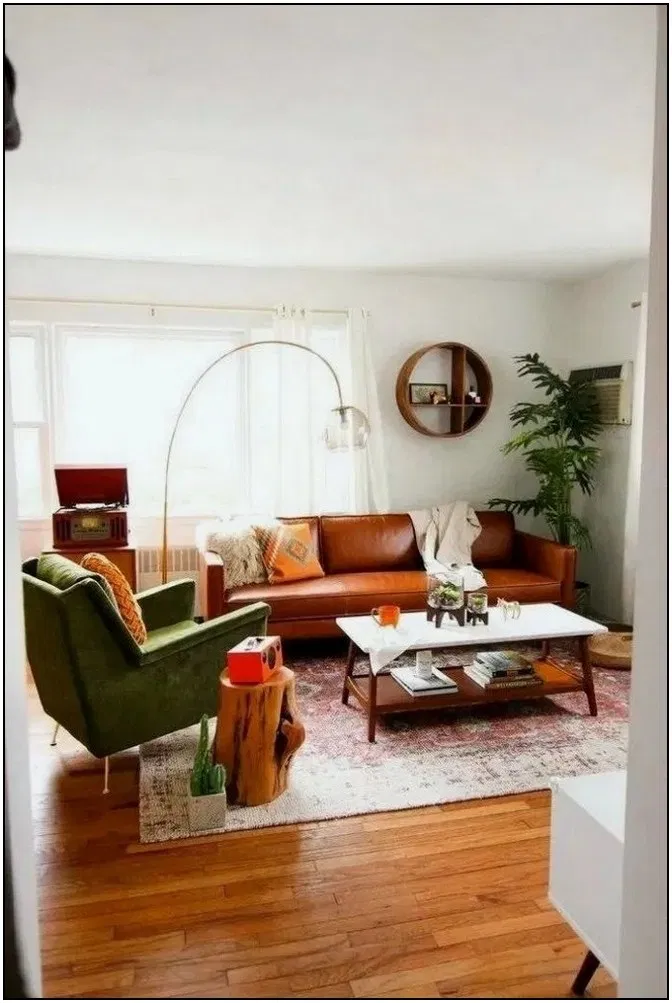 living room, wooden floor, white wall, red rug, brown leather sofa, green leather chair, wooden coffee table with white top