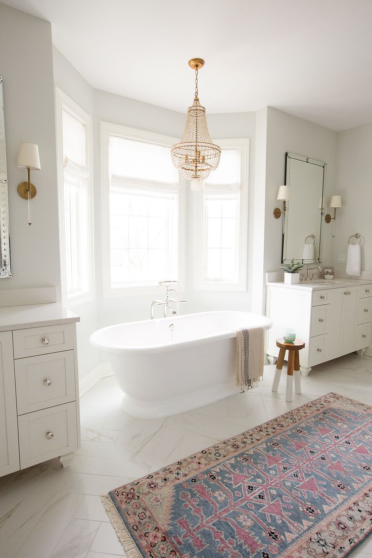 bathroom, white marble floor, patterned rug, white wall, white cabinet, mirror, chandelier, white sconces