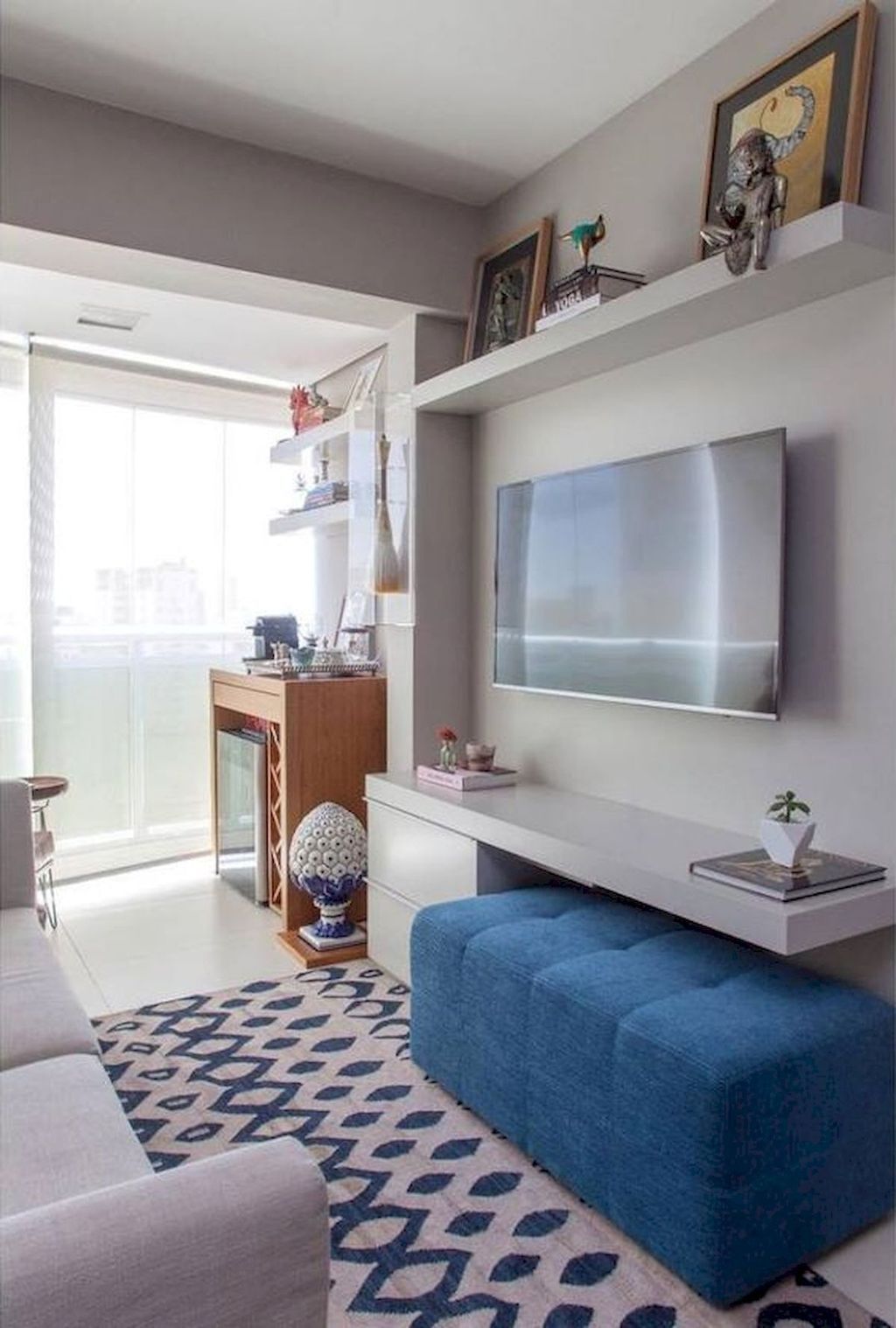 small living room, white floor, white cabinet, TV, blue tufted bench, white sofa, patterned sofa, floating shelf, chair, cabinet