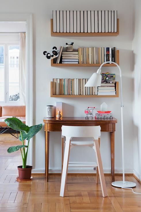 small study, wooden table, white wall, wooden floating shelves, white floor lamp, white wooden chair