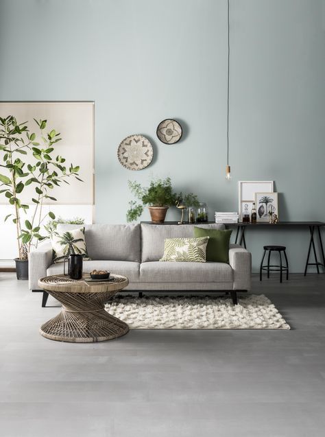 living room, grey wooden floor, blue wall, gey sofa, rattan coffee table,white rug, black table, black stool