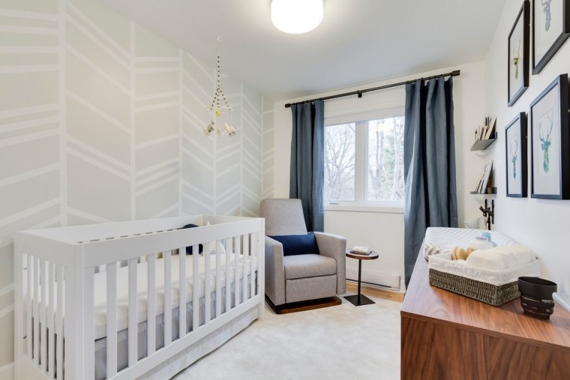 white theme room with white cirb, grey couch, stag head paintings, grey curtain, wooden cabinet and diaper changing area on top of it