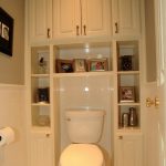 Bathroom With White Wall, White Toilet, White Shelves And White Cabinet Surrounded The Toilet From The Top